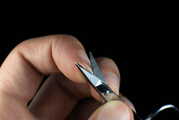 Man is making a manicure scissors. Procedures at home. Cutting nails.