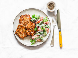 Delicious chicken fillet, apple fritters and fresh vegetables yogurt dressing salad on a light background, top view