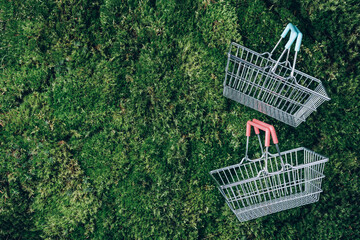 Top view of supermarket shopping basket on green grass, moss background. Minimalism style. Black friday sale, discount, shopaholism, ecology concept. Sustainable lifestyle, conscious consumption - obrazy, fototapety, plakaty