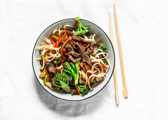 Udon noodles with beef and vegetables - delicious lunch on a light background, top view. Balanced food