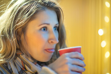 Young beautiful woman is drinking coffee in a cafe in the evening.