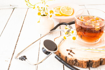 Decoction of chamomile, dried flower in flower tea and a phonendoscope, sliced lemon on a white...