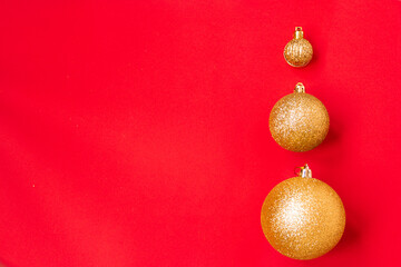 Three golden Christmas balls of different sizes are displayed in a row as a border on a red background. New Year mood mok up. Copy space
