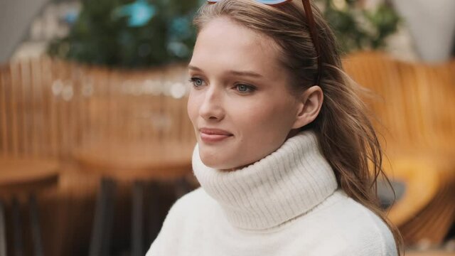 Portrait of beautiful smiling girl dressed in white collared sweater looking happy outdoor