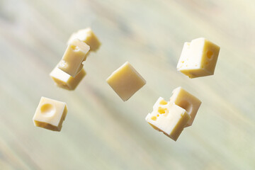 Cheese cubes in the air on a wooden background.