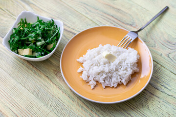 White boiled rice and greens salad on a wooden background. Healthy food concept.