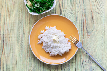 White boiled rice and greens salad on a wooden background. Healthy food concept.