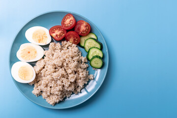 Healthy food, diet. Barley porridge and chicken eggs on a blue background.