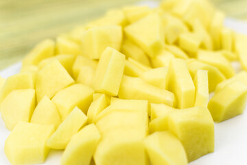 Peeled and cut raw potatoes on a white board.