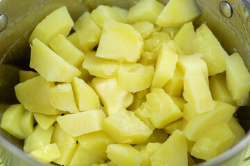Boiled potatoes in pieces in a saucepan with butter.