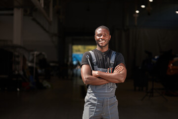 portrait of positive afro american auto mechanic in uniform posing after work, he is keen on repairing cars, automobiles.