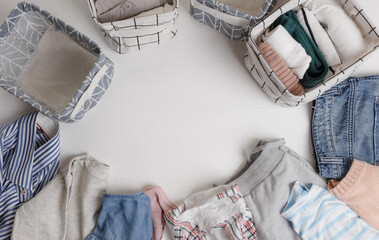 A group of organic cotton clothing set on a white table is ready to be folded into white baskets.The concept of closet organization. Colors in the Scandinavian style. Using the Komari method.