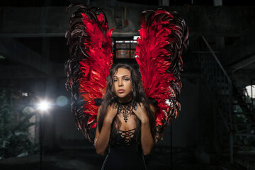 Close up portrait of a Delicate beautiful brunette woman posing with  red dark angel wings. Studio shot.