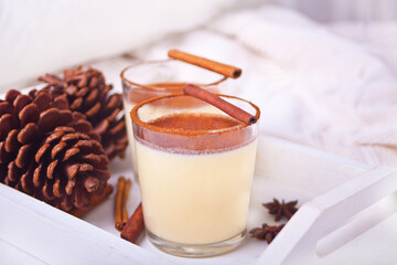 Glasses of holiday egg nog on the wooden white tray