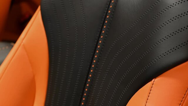 Black and orange perforated leather on the seats of a modern sports car.