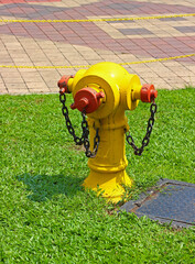 Typical old yellow fire hydrant with rusty chains on the lawn in Kuala Lumpur city on a sunny day