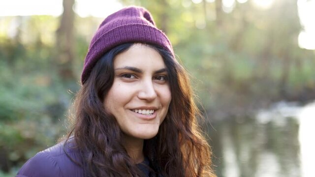 Close-up of beautiful woman smiling next to a river in the forest