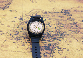 Classic round compass on background of old vintage map of world as symbol of tourism with compass, travel with compass and outdoor activities with compass