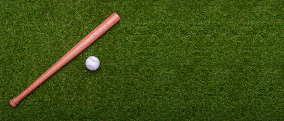 Baseball bat and ball on green grass field.  Sport theme background with copy space for text and...