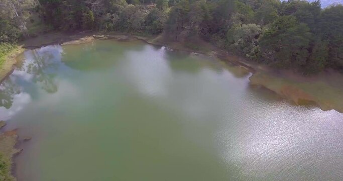 Pristine Green Guarne Lagoon in the Middle of the Woods near Medellin, Colombia on a Cloudy Day shot from in Smooth Travelling form Above