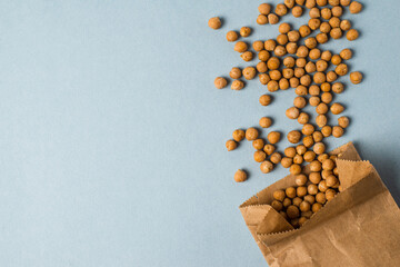 chickpea  are scattered randomly and paper bag on a bright blue background. Space for text. For advertising, media, concepts of healthy lifestyle and vegan organic food concepts