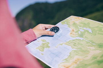 Hand of woman looking on map and compass to checking her position.