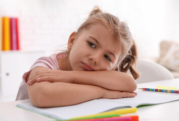 Tired little girl at table. Doing homework