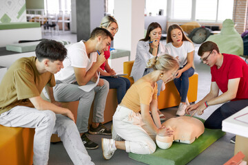 CPR class with male instructor speaking and demonstrating help, giving lessons of first aid. compression and resuscitation procedures. Cpr mannequin is used for an example