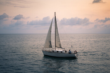Obraz premium Sailing boat in the sea at sunset