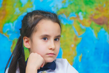 Close-up portrait of smart cute girl on the background of the world map.