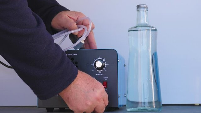 Bottle of iced water being ozonated with a round ozonating stone. Tubes leading to oxygen pump and ozone generator