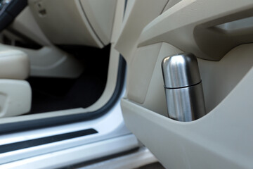 Silver thermos in door storage pocket inside car