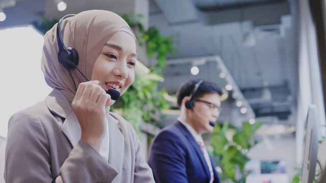 Muslim woman work as a Call Center In a modern office by social distancing with colleagues. Information service, consultation or video conference. Concept key worker