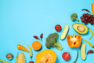 Flat lay composition with fresh organic fruits and vegetables on light blue background. Space for text