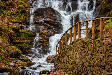 waterfall in the autumn forest with authentic wooden handrails. wallpaper, screensaver, poster