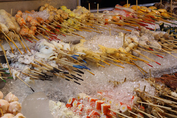 Chilled skewers for barbecue at Jalan Alor food street in Kuala Lumpur. Popular Asian food. Large pile of satay skewers on ice in Asia. Photo taken in low light at night
