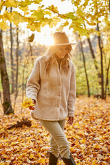 fashionable pretty woman walking outdoors in autumn spring park or forest, she contemplates everything around, wearing warm clothes and hat