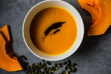 Homemade, fresh and good looking  pumpkin soup in white bowl on beautiful background, flat lay, close up.