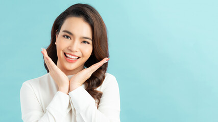 Fototapeta premium Portrait of an excited asian woman looking at camera isolated over blue background