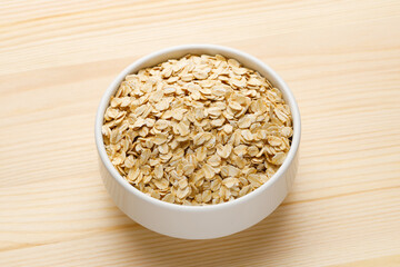 Cup of dry oatmeal on a wooden table.