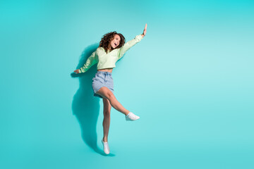 Fototapeta na wymiar Full length body size photo of brunette girl dancing jumping keeping hand up singing isolated on vibrant teal color background