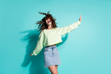 Photo portrait of laughing woman dancing making plane with hands isolated on vivid cyan colored background