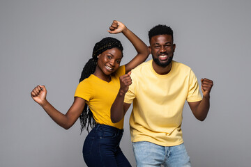 Fototapeta na wymiar Overjoyed african American man and woman happy for win, excited ethnic couple in spectacles feel overjoyed receiving good news being successful isolated on grey studio background