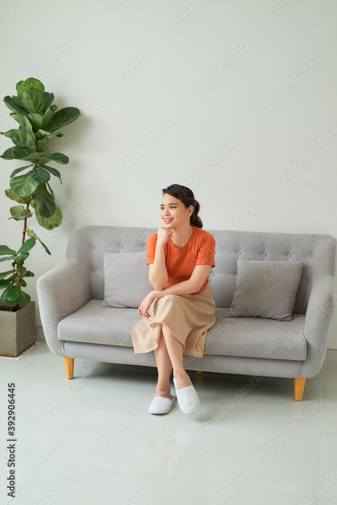 Wall mural attractive asian woman sitting on the sofa