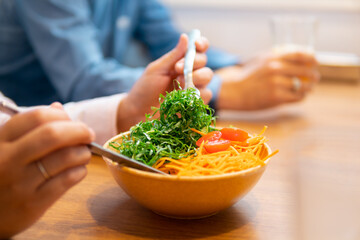 close up detail of female hands grabbing salad in a bowl at office cafeteria. .