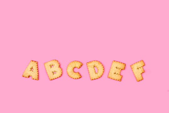 Letras hechas de galletas sobre un fondo rosa liso y aislado. Vista superior. Copy space