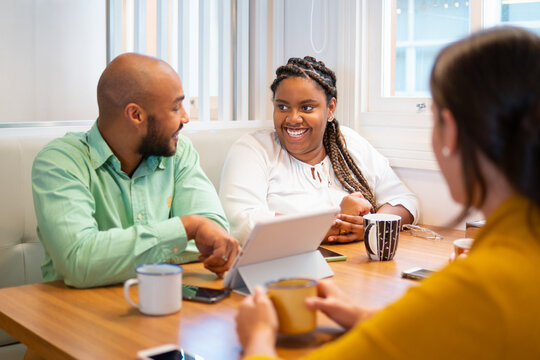 Latin african american woman talking causally with co-workers during break at cafeteria. Communication, cooperation, brainstorm concept.. - Powered by Adobe