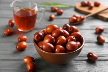 Palm oil fruits in bowl on grey wooden table, closeup
