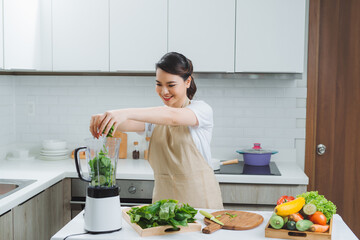 Vegetable smoothie woman blending green smoothies with blender home in kitchen