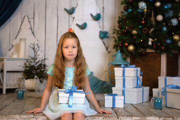 Obraz premium girl sitting on the wooden floor in a mint dress. holding a gift.